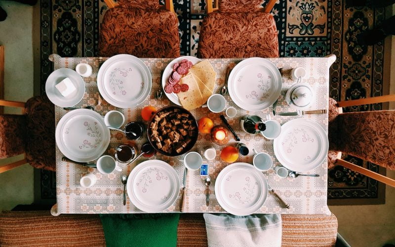 high angle photography of dinner set on table surrounded with padded chairs