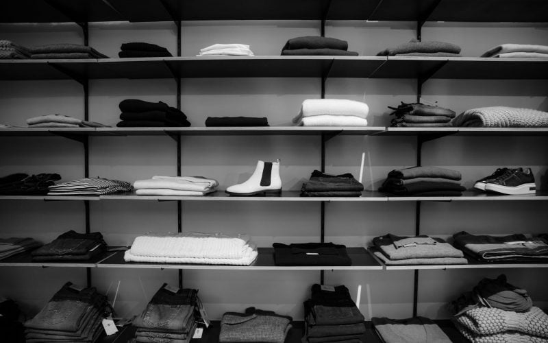 grayscale photography of assorted apparels on shelf rack